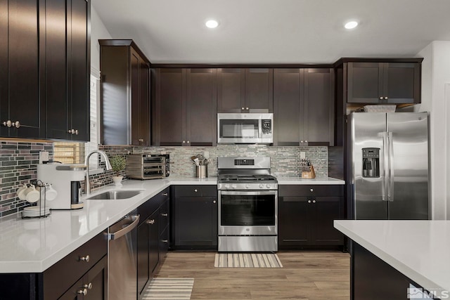 kitchen featuring stainless steel appliances, sink, backsplash, and dark brown cabinetry