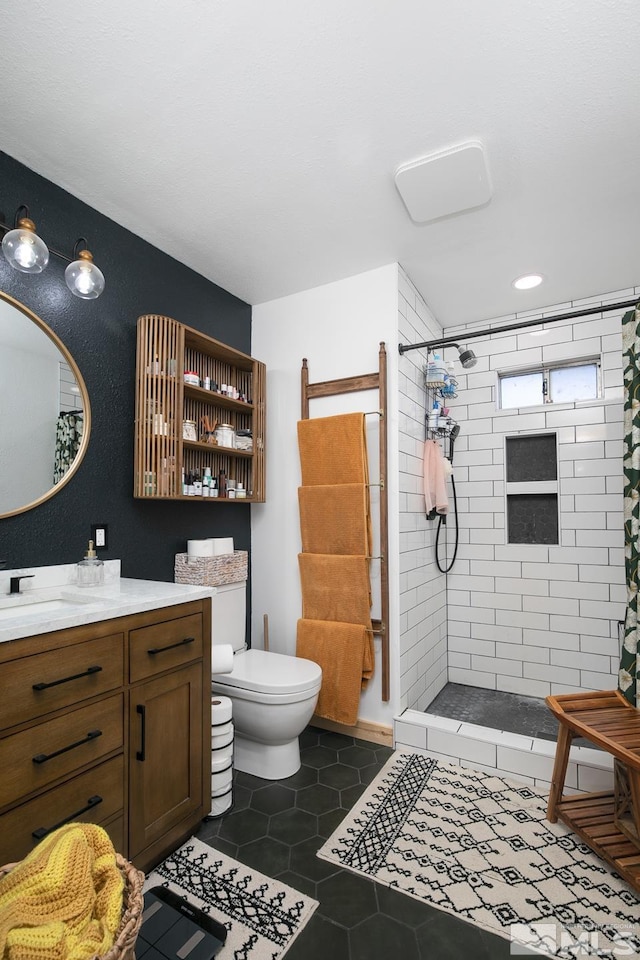 bathroom featuring a tile shower, vanity, tile patterned floors, and toilet