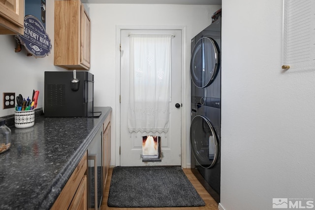 laundry area featuring light hardwood / wood-style floors, cabinets, and stacked washing maching and dryer