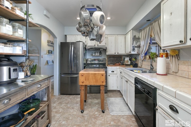 kitchen with tile countertops, white cabinetry, sink, backsplash, and stainless steel appliances