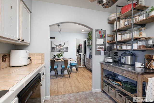 bar with tile counters, dishwasher, and white cabinets