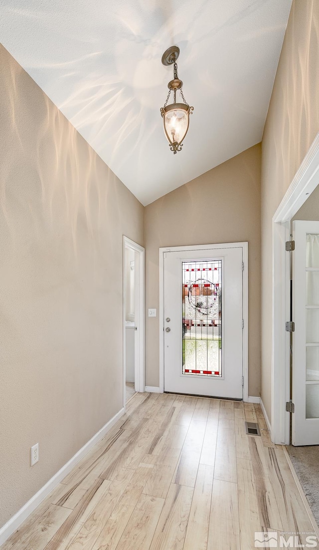 entryway featuring lofted ceiling and light hardwood / wood-style flooring