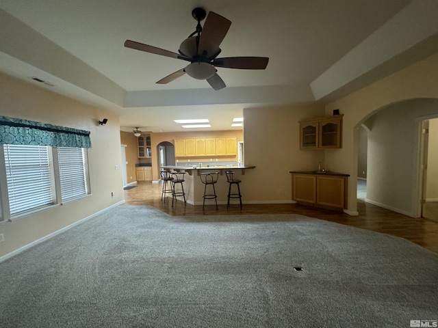 unfurnished living room featuring a tray ceiling and ceiling fan