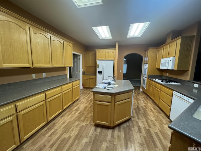 kitchen featuring hardwood / wood-style floors, white appliances, light brown cabinets, and a kitchen island