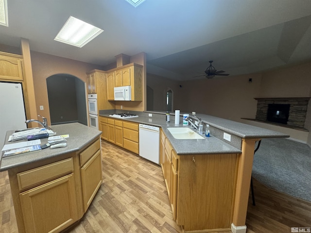 kitchen with light brown cabinetry, sink, light wood-type flooring, an island with sink, and white appliances