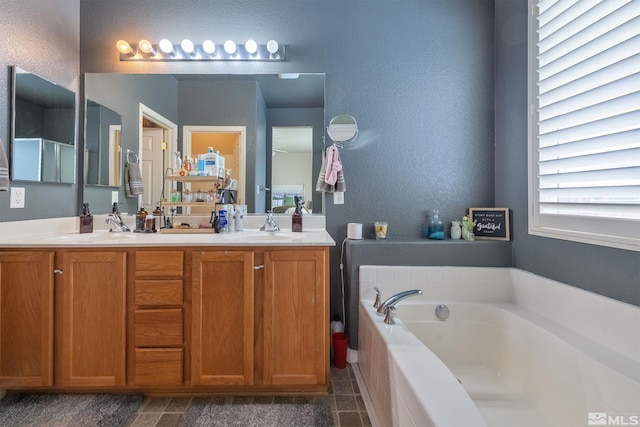 bathroom featuring tiled tub and vanity