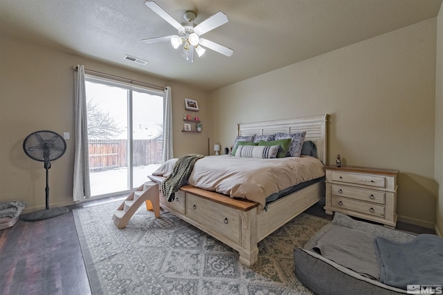 bedroom with access to exterior, a textured ceiling, hardwood / wood-style floors, and ceiling fan