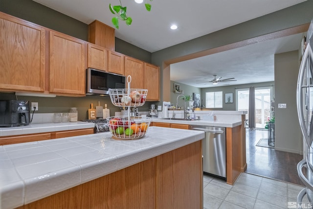 kitchen featuring stainless steel appliances, sink, tile counters, and kitchen peninsula