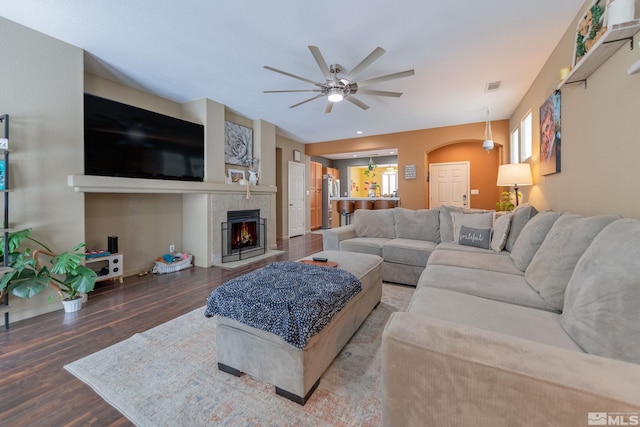 living room featuring ceiling fan, dark hardwood / wood-style flooring, and a tile fireplace