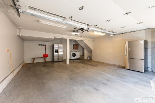 garage featuring stainless steel refrigerator, a garage door opener, stainless steel fridge, and washer / clothes dryer