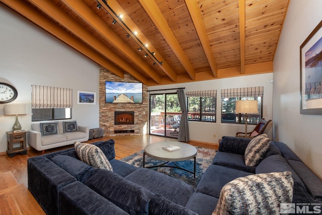 living room featuring high vaulted ceiling, a fireplace, beamed ceiling, wood ceiling, and light hardwood / wood-style flooring