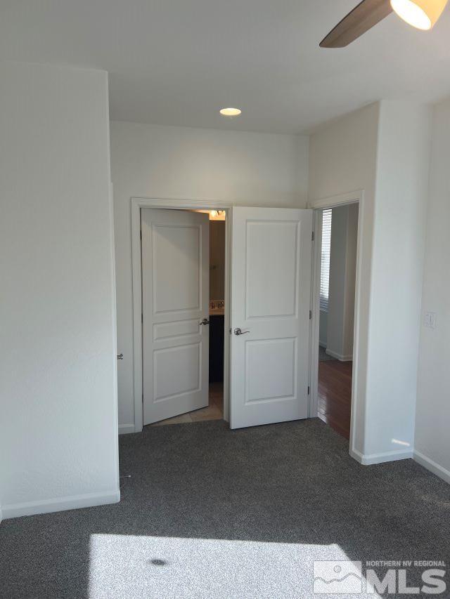 spare room with dark carpet and ceiling fan