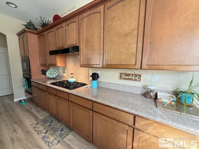 kitchen with light stone countertops, light hardwood / wood-style flooring, and black appliances