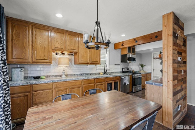 kitchen featuring sink, appliances with stainless steel finishes, butcher block counters, tasteful backsplash, and decorative light fixtures