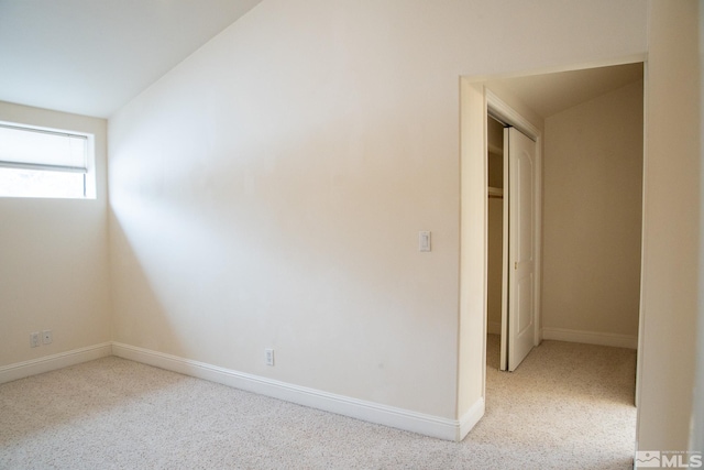 spare room with vaulted ceiling and light carpet