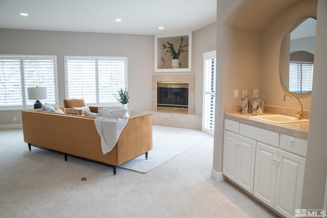 carpeted living room featuring a premium fireplace and sink