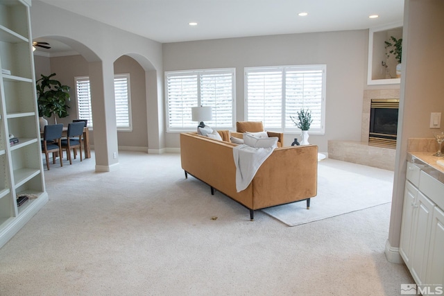 living room with built in features, a tile fireplace, and light carpet