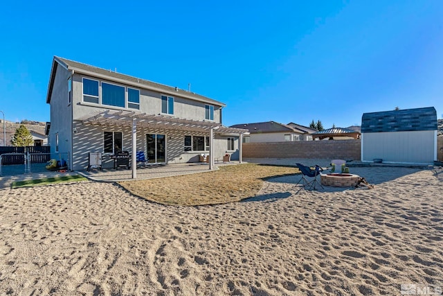 back of house featuring a fire pit, a pergola, a patio area, and a shed