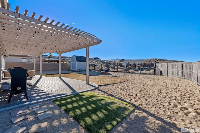 view of yard featuring a patio, a pergola, a mountain view, and a storage unit