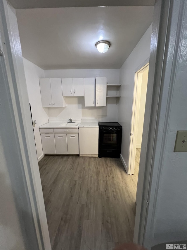 kitchen with black range with electric stovetop, dark wood-type flooring, sink, and white cabinets