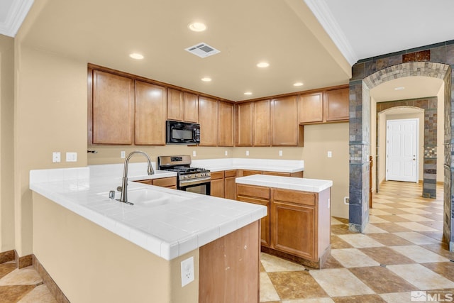 kitchen featuring sink, stainless steel gas stove, crown molding, tile countertops, and kitchen peninsula