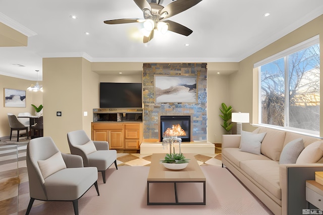 living room with ceiling fan, ornamental molding, and a stone fireplace