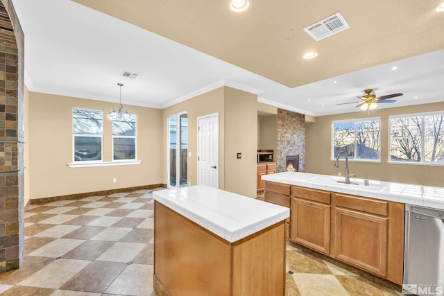 kitchen featuring sink, a center island, stainless steel dishwasher, tile counters, and pendant lighting