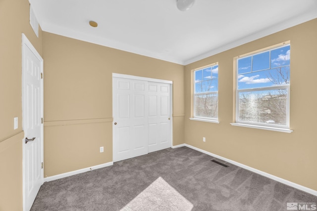 unfurnished bedroom with ornamental molding, carpet floors, and a closet