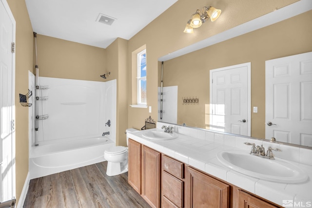 full bathroom with shower / washtub combination, toilet, hardwood / wood-style floors, and vanity