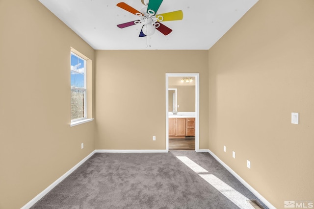 unfurnished bedroom with ceiling fan, connected bathroom, and carpet