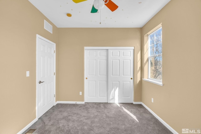 unfurnished bedroom with ceiling fan, a closet, and light carpet