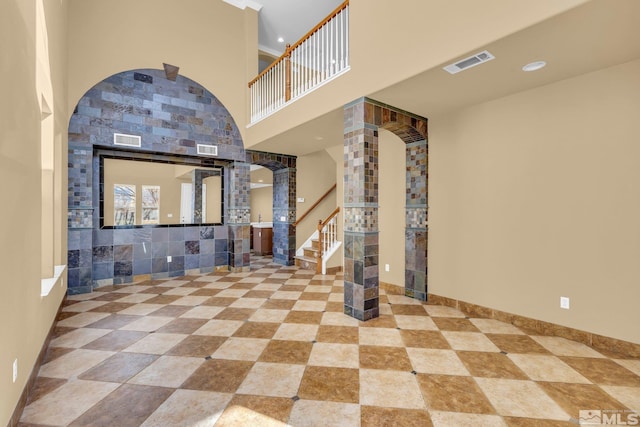 entryway featuring a towering ceiling and ornate columns