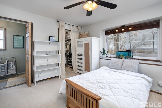 bedroom with ceiling fan, a spacious closet, light colored carpet, and a closet