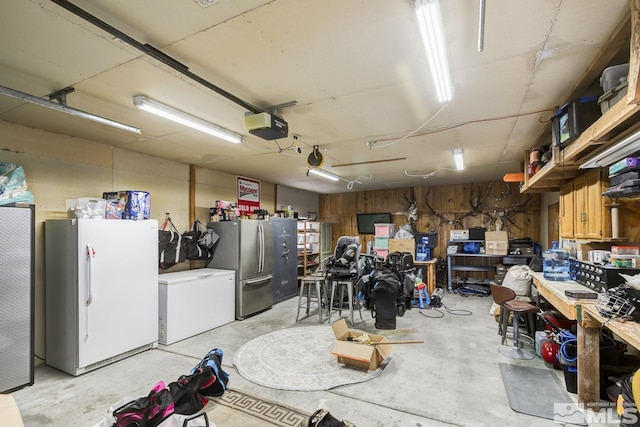 garage featuring a garage door opener, white refrigerator, fridge, stainless steel refrigerator, and a workshop area