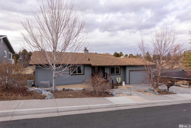 single story home featuring cooling unit and a garage