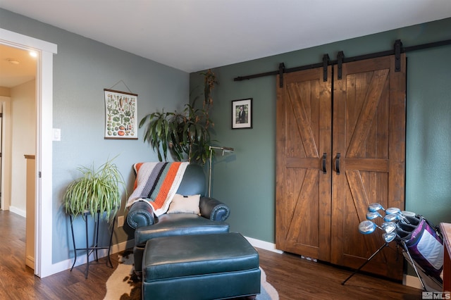 sitting room with a barn door and dark hardwood / wood-style flooring