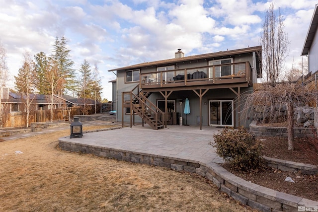 back of house with a wooden deck and a patio