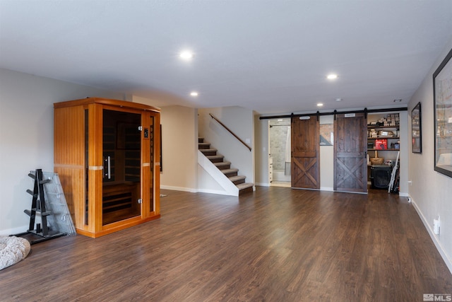 unfurnished living room with a barn door and dark wood-type flooring