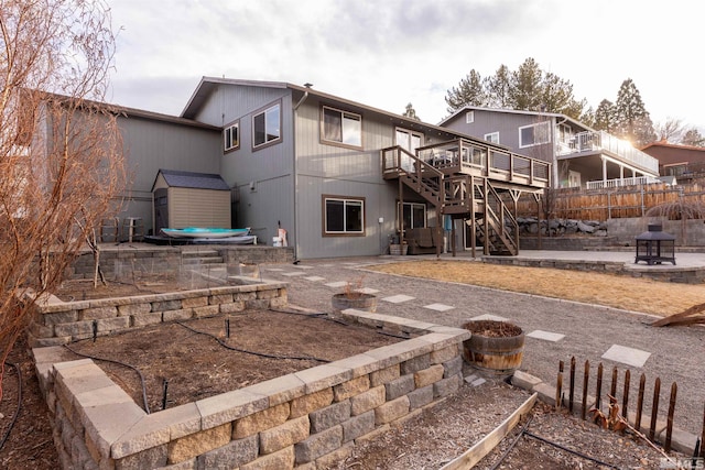 back of house featuring a wooden deck, a fire pit, a patio, and a storage unit