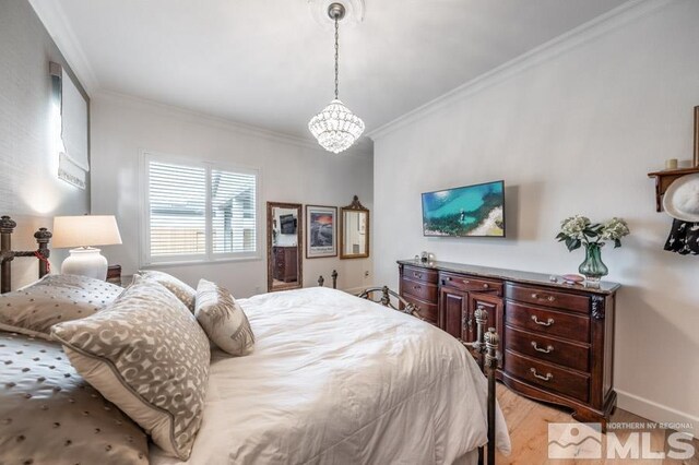 bedroom featuring a notable chandelier, crown molding, and light hardwood / wood-style floors