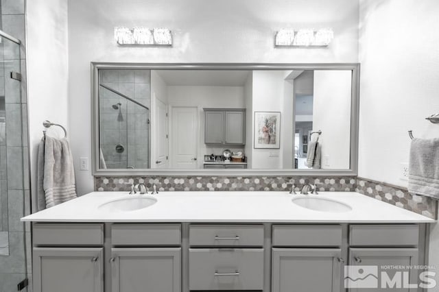 bathroom with vanity, decorative backsplash, and a shower with shower door