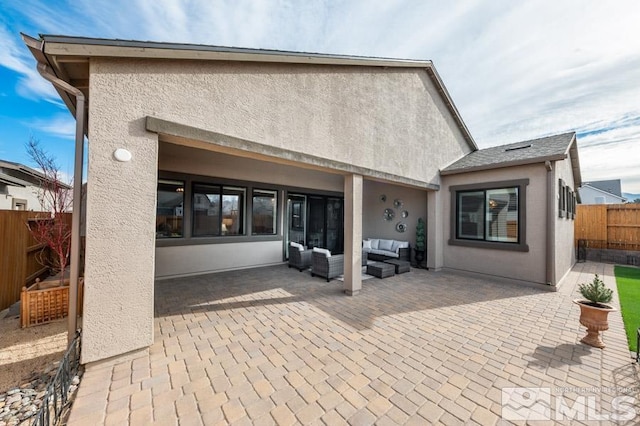 back of property with an outdoor living space and a patio