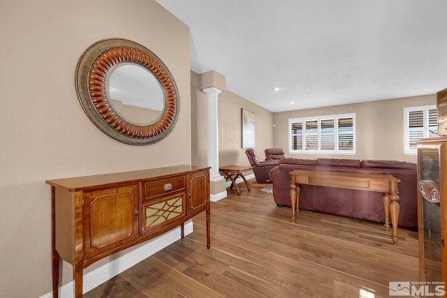 living room with decorative columns and light hardwood / wood-style floors