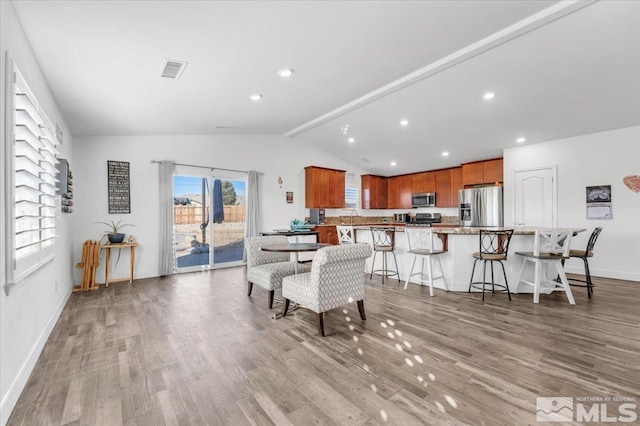 dining room featuring lofted ceiling with beams and light hardwood / wood-style floors