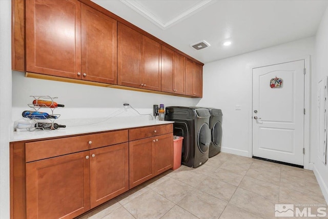 clothes washing area with cabinets, crown molding, light tile patterned floors, and washer and clothes dryer