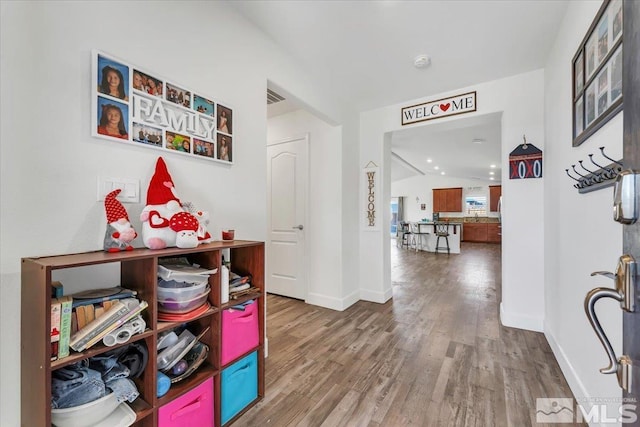 corridor with lofted ceiling and hardwood / wood-style floors