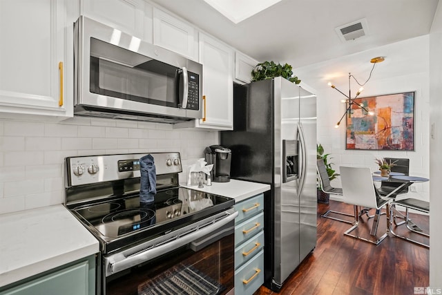 kitchen featuring appliances with stainless steel finishes, dark hardwood / wood-style floors, white cabinets, backsplash, and a notable chandelier