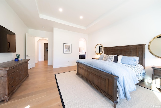 bedroom featuring a tray ceiling and light hardwood / wood-style flooring