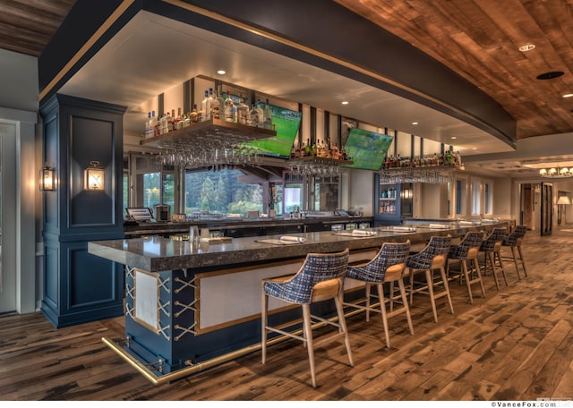 bar with blue cabinetry, wood ceiling, dark hardwood / wood-style flooring, and dark stone counters