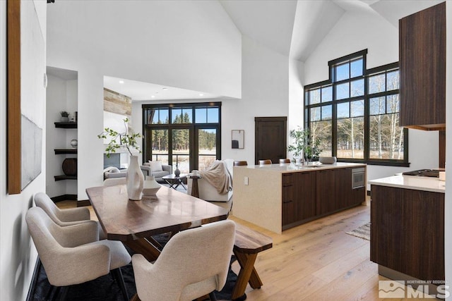 dining area with high vaulted ceiling and light wood-type flooring